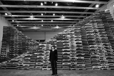 The artist Liz Glynn’s new installation at Mass MoCA includes three caves fashioned from forklift pallets. Glynn, above, was on hand last month to assemble the show, “The Archaeology of Another Possible Future,” which grapples with the idea of economic progress. Jack Criddle photo