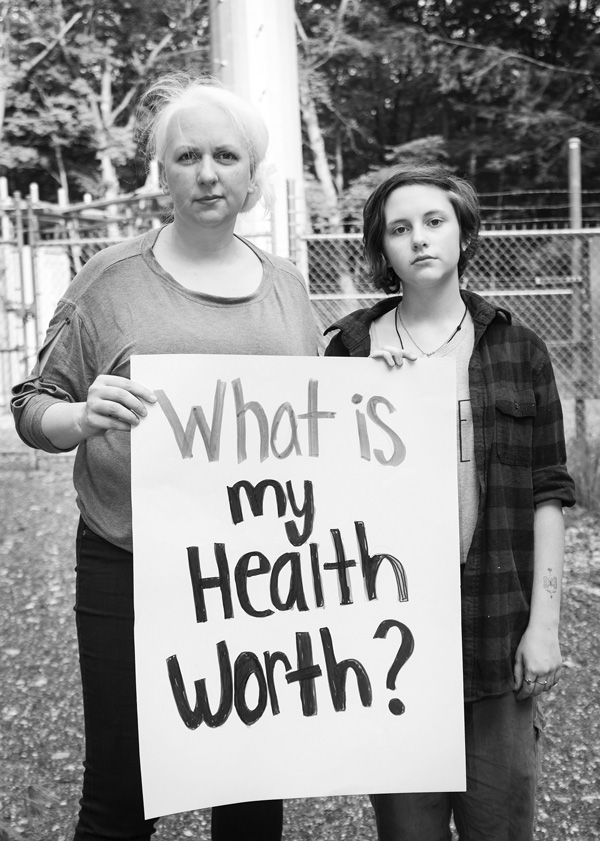 Courtney Gilardi stands with one of her daughters at the base of a cell phone tower that was built two years ago behind their home. The Gilardis and their neighbors say the tower has been making them sick. Susan Sabino photo