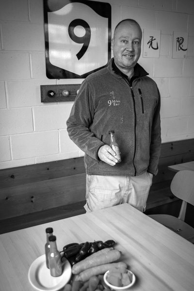 Gordon Sacks holds a bottle of one of the new line of hot sauces made from ingredients grown at 9 Miles East Farm. Joan K. Lentini photo