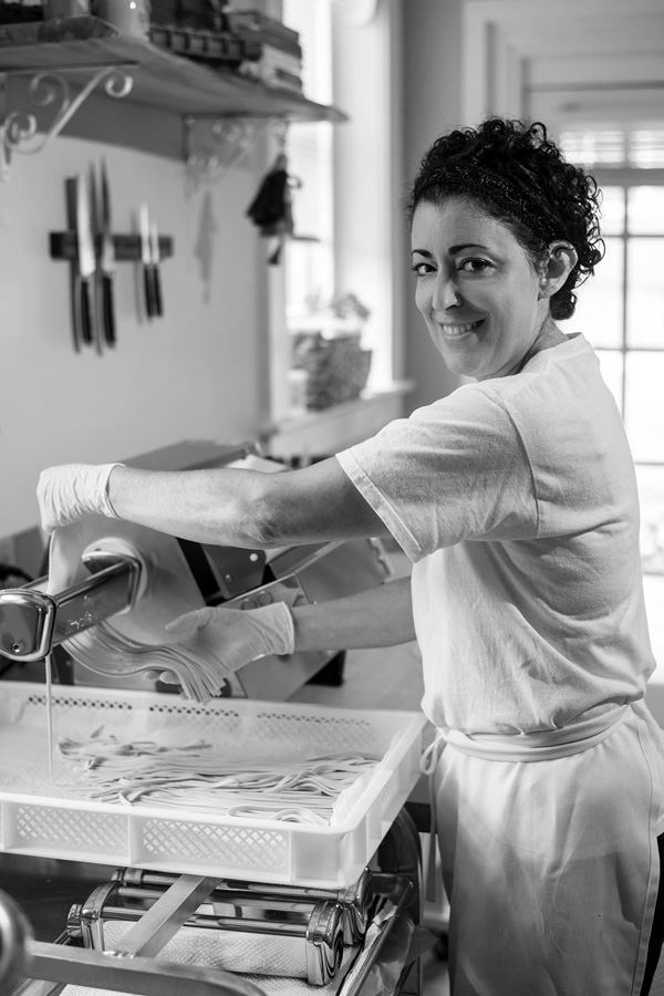 Rose Contadino feeds her rolled dough through a pasta cutter to turn it into fettuccine noodles at her shop in Saratoga Springs. Joan K. Lentini photo